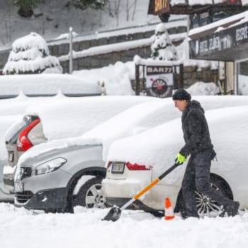 Muž odklízí sníh před hotelem ve Špindlerově Mlýně.