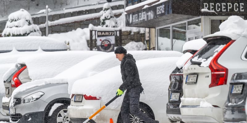 Muž odklízí sníh před hotelem ve Špindlerově Mlýně.