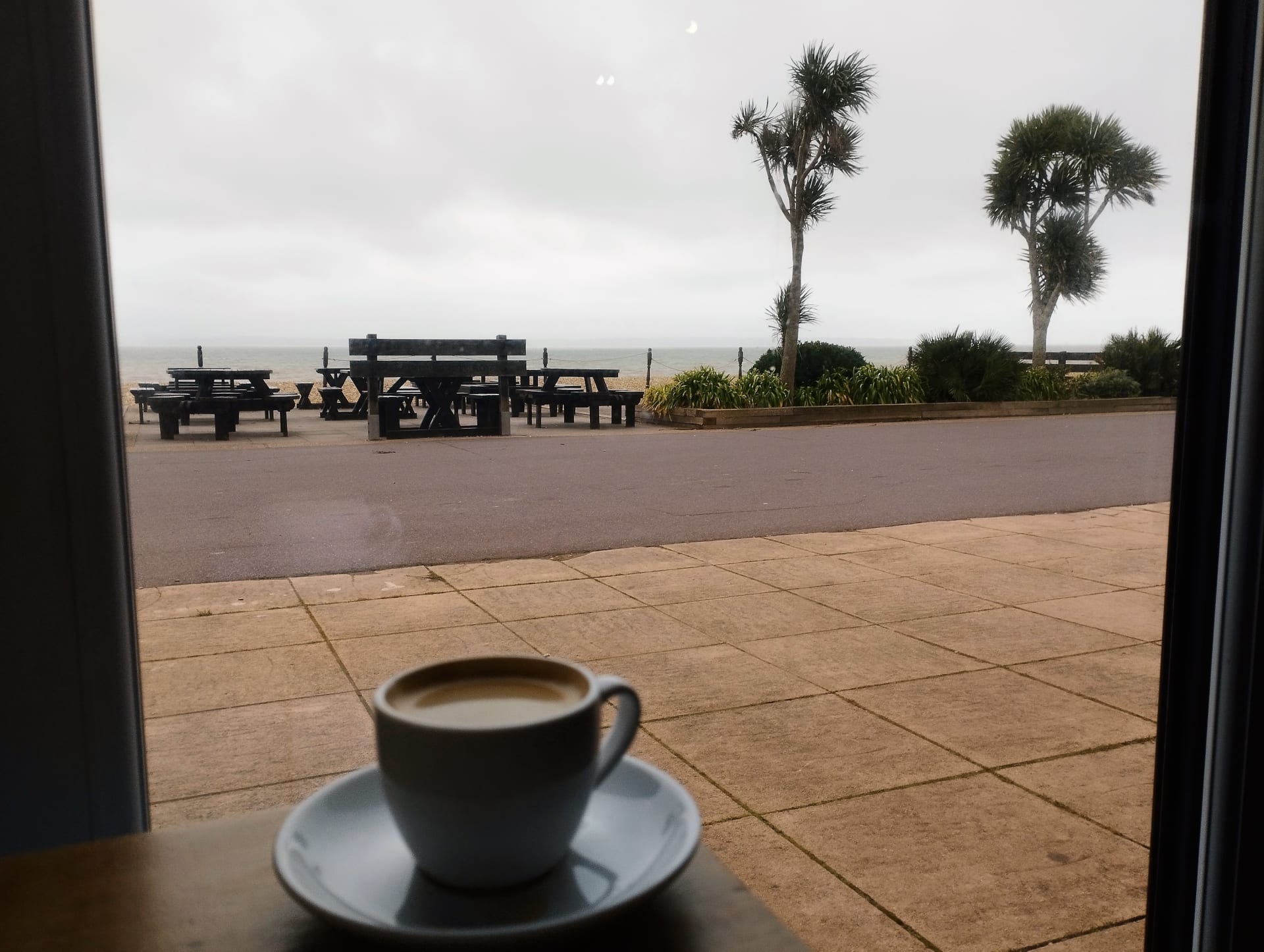 Pebbles Cafe s výhledem na moře. Espresso zde stojí 69 Kč. Gosport, jižní Anglie, únor 2023