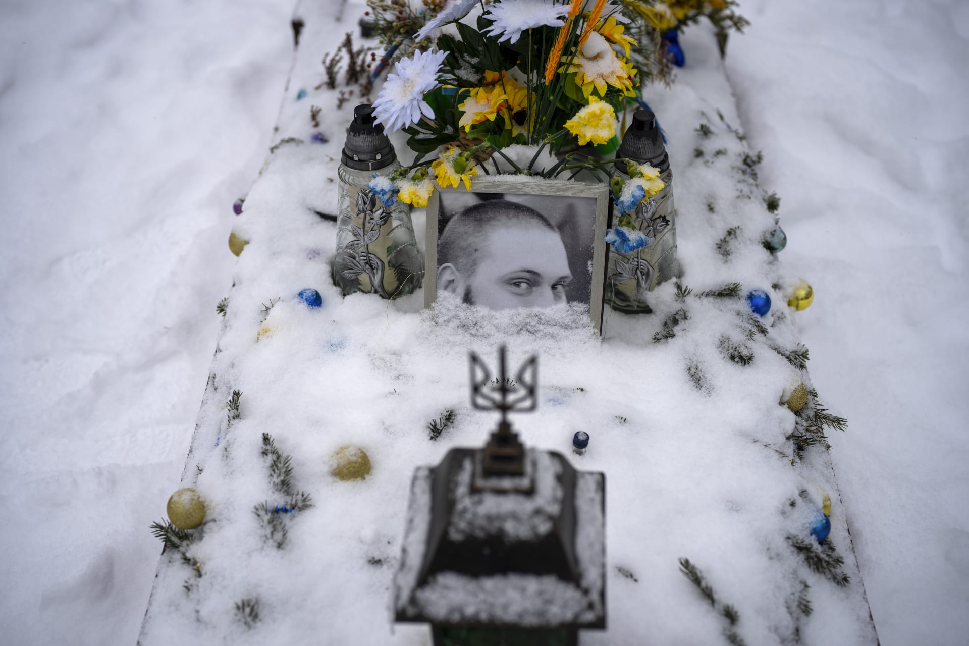 Portrét 30letého seržanta Oleksandroviče Sixoje, částečně zasypaný sněhem, na jeho hrobě ve Lvově. Byl zapit 13. dubna 2022. (7.2.2023)