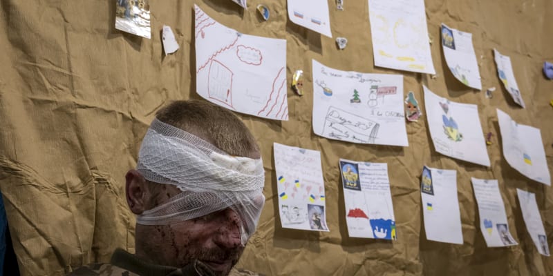 Zraněný voják čeká na evakuaci, zatímco v nemocnici poblíž fronty 22. února 2023 v Donbasu na východě Ukrajiny visí dětské kresby a přání všeho dobrého. 