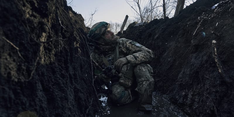 Ukrajinský voják se kryje v zákopu před ruským ostřelováním na frontové linii u Bachmutu.