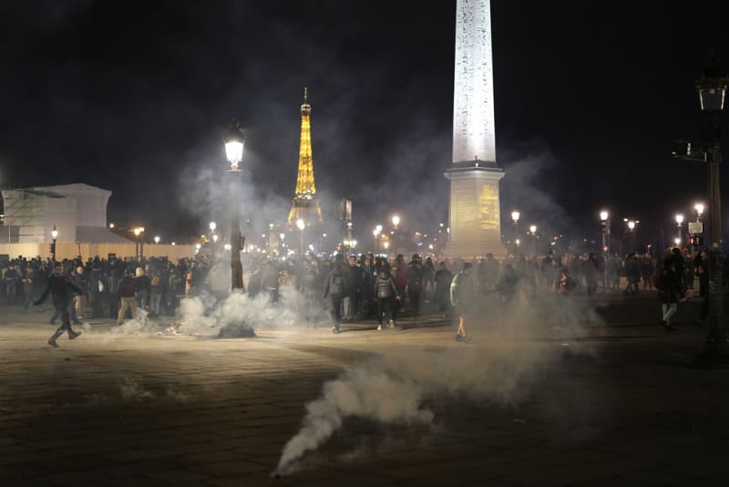 Protestující stojí v oblaku slzného plynu po demonstraci v Paříži, čtvrtek 16. března 2023.