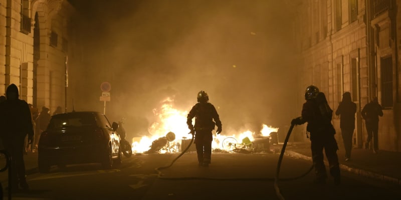 Hasiči hasí požár u náměstí Concorde po demonstraci v Paříži, čtvrtek 16. března 2023.