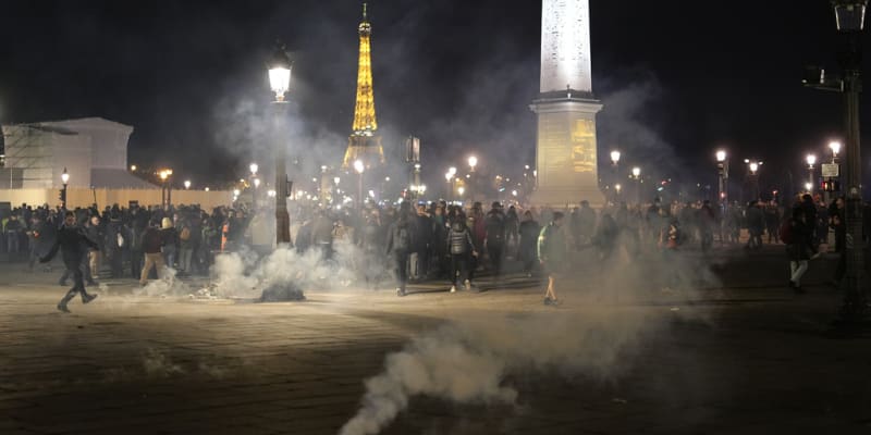 Protestující stojí v oblaku slzného plynu po demonstraci v Paříži, čtvrtek 16. března 2023.