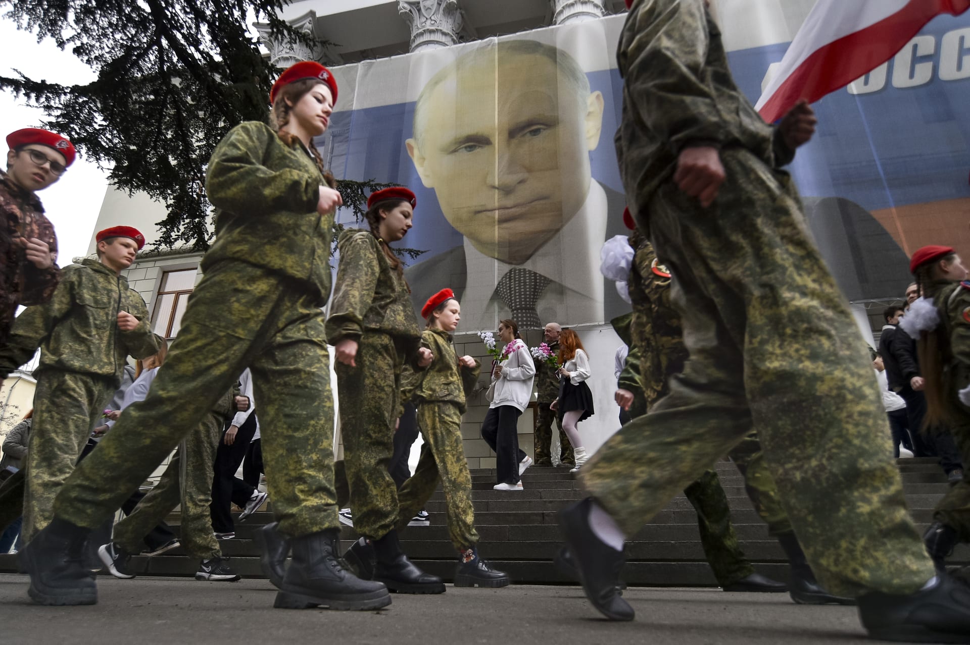 Děti pochodují v průběhu příprav na příjezd Vladimira Putina na Krym u výročí jeho anexe. „Rusko nezačíná války, ukončuje je,“ stojí na plakátu v pozadí. (17. 3. 2023)