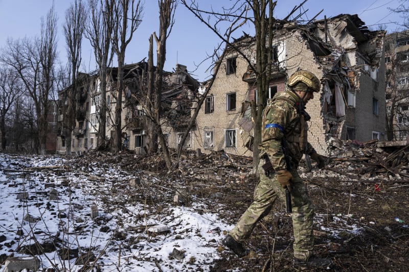 Voják před zdevastovanými budovami v Avdijivce (7. 3. 2023)