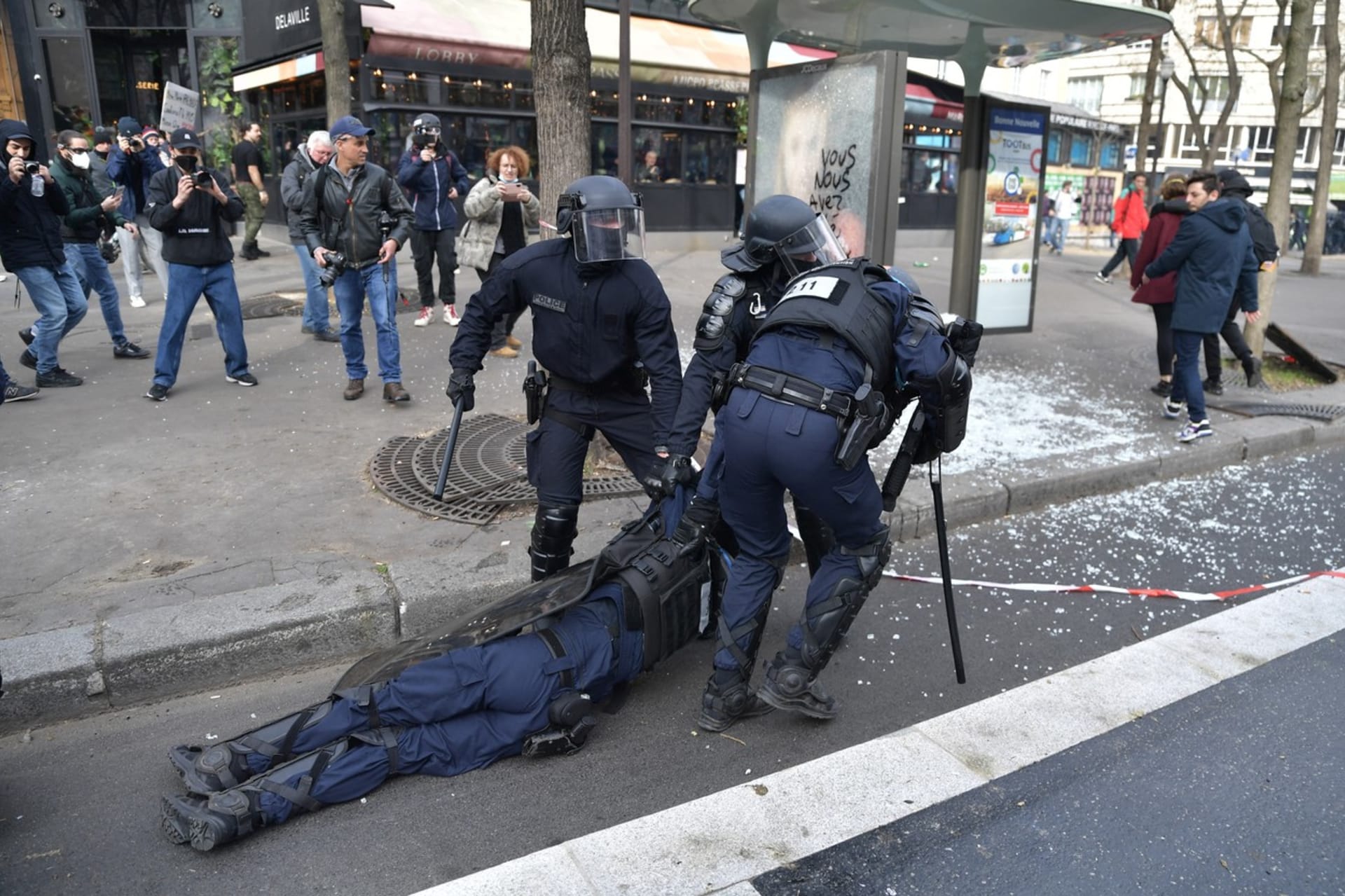 Pořádková policie vleče svého omdlelého kolegu při  střetech s demonstranty během protestu proti vládě, Paříž, 23. března 2023.