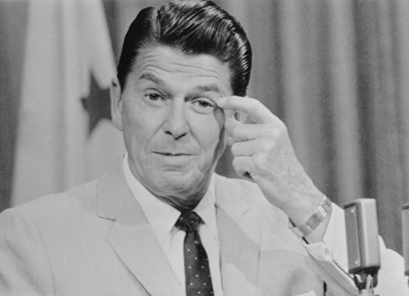 Ronald Reagan si nervózně sahá na tvář poté, co se ho reportéři zeptali, zda bude o víkendu při setkání s Richardem Nixonem v Bohemian Grove projednávat politické záležitosti