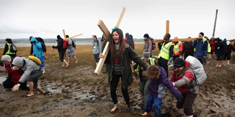 Poutníci nesou symbolické kříže na Svatý ostrov poblž Berwick-upon-Tweed v severovýchodní Anglii