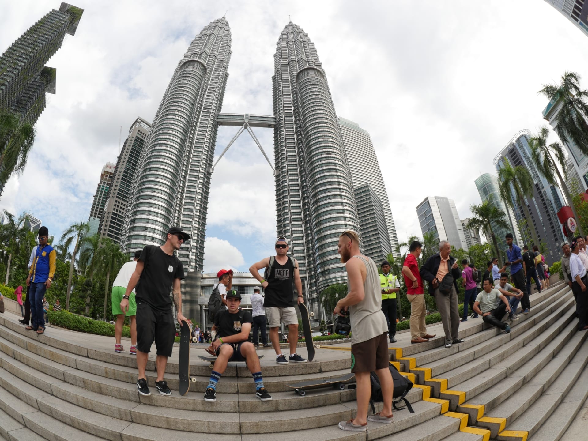 Celá SkateTripping parta před ikonickými mrakodrapy Petronas Towers v Kuala Lumpur