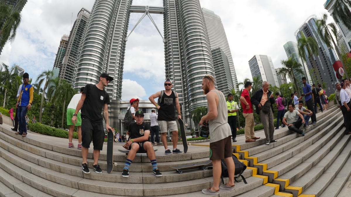 Celá SkateTripping parta před ikonickými mrakodrapy Petronas Towers v Kuala Lumpur