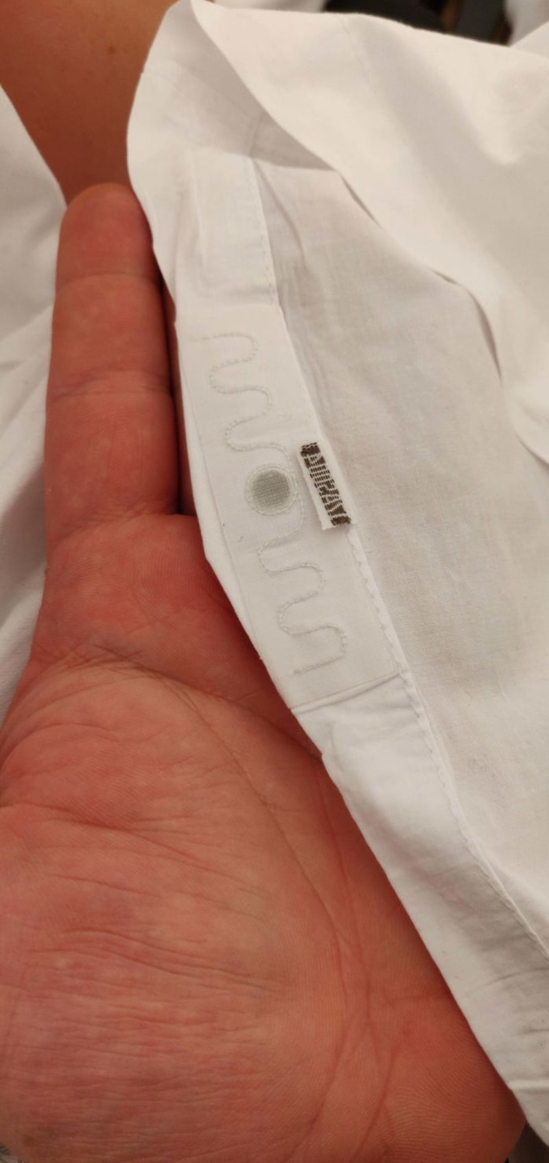 Divná věc všitá do hotelového povlečení - Pravděpodobně jde o RFID čip sloužící k identifikaci povlečení v průmyslových prádelnách.