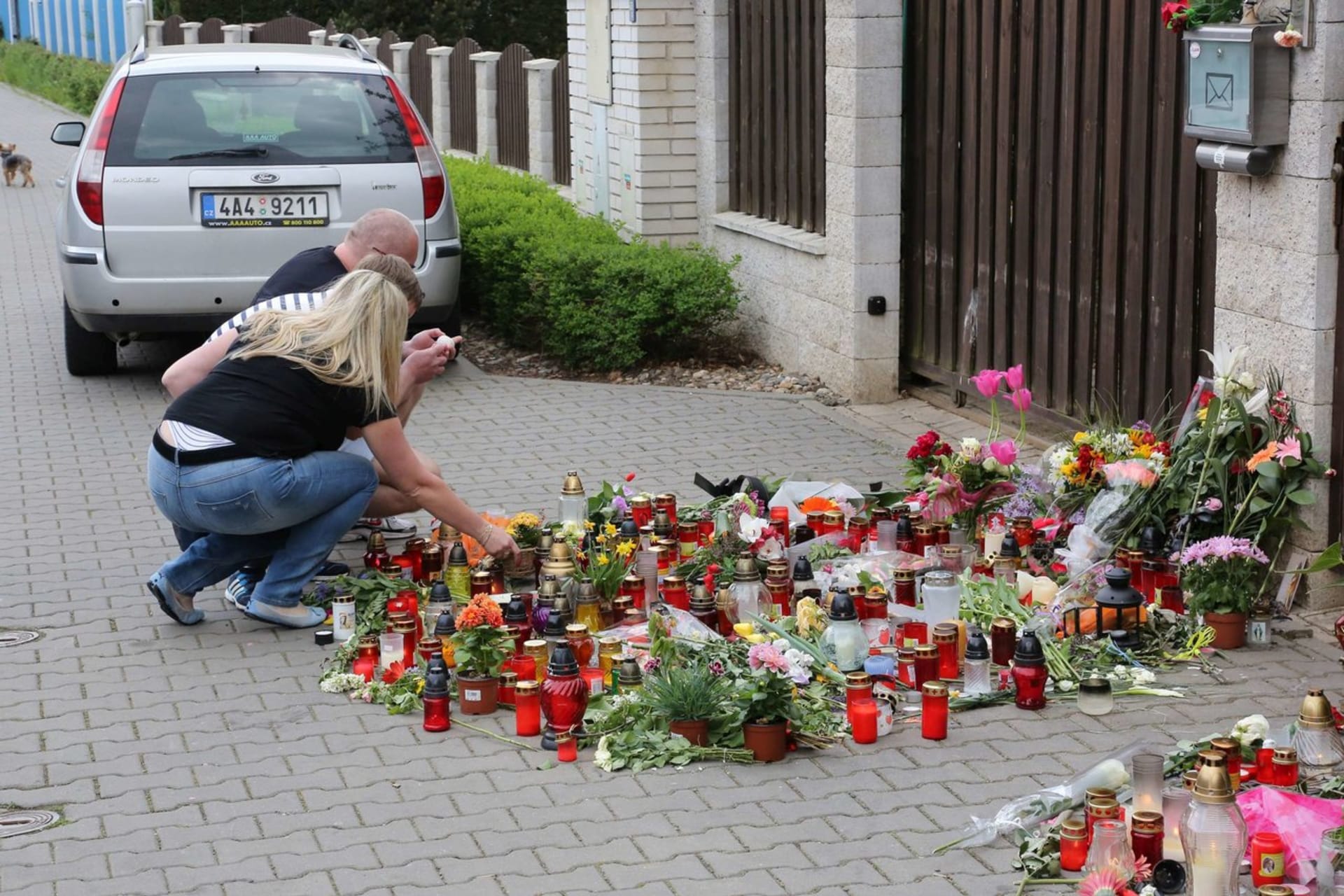 Lidé chodí spontánně k domu, kde bydlela Iveta Bartošová, pokládat zapálené svíčky a květiny