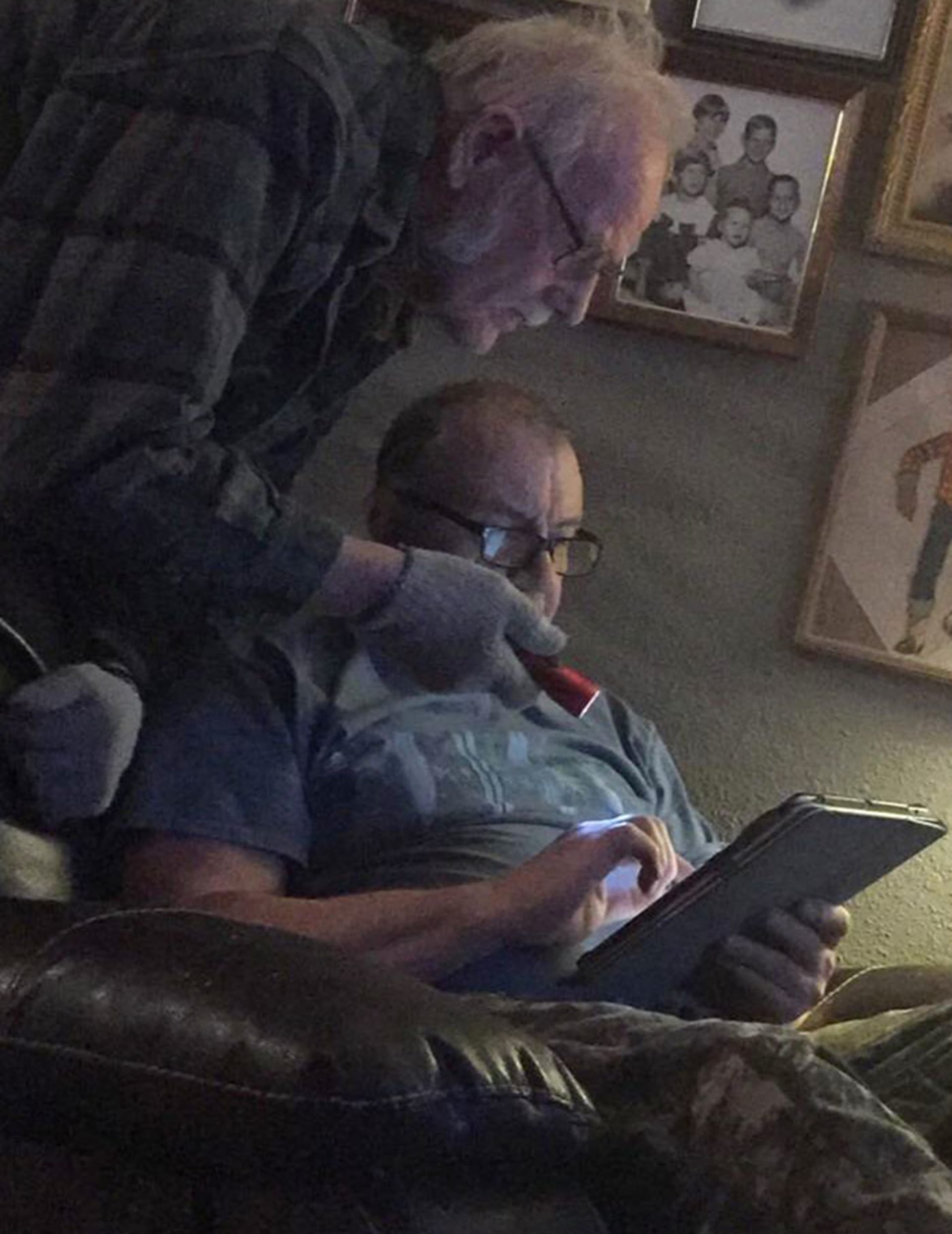 Děda si svítí baterkou na iPad, aby lépe viděl