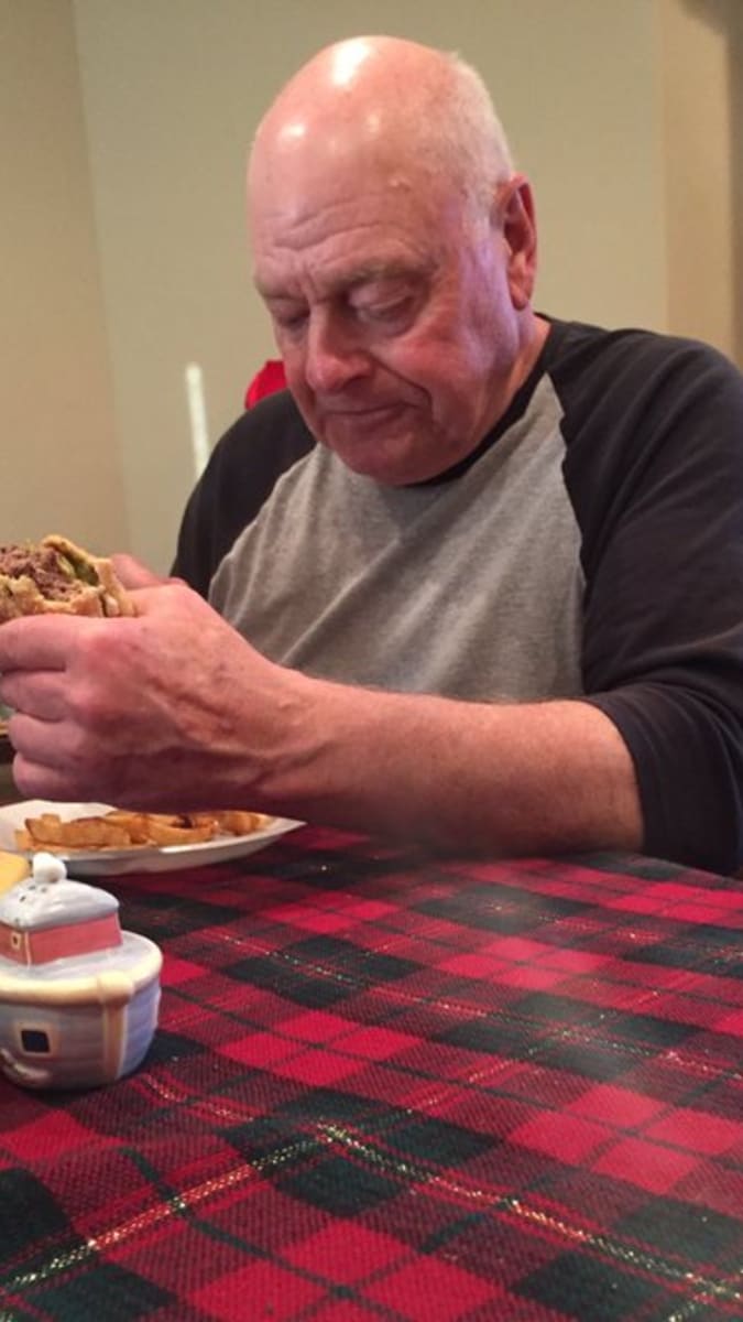 Smutný děda jí sám burger.