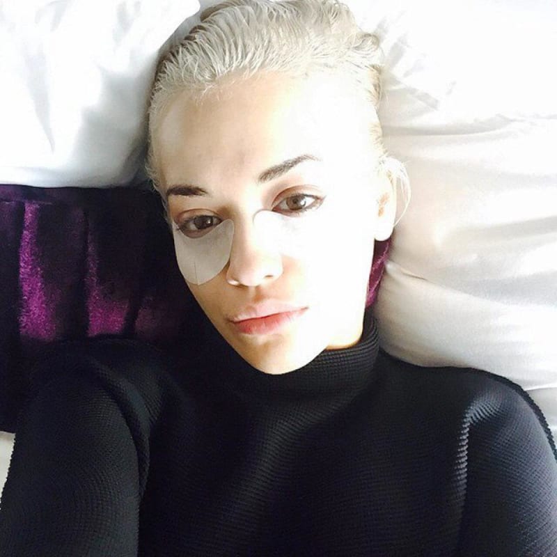 Předoscarová příprava. Zpěvačka Rita Ora leží ve své posteli s maskou proti kruhům pod očima.