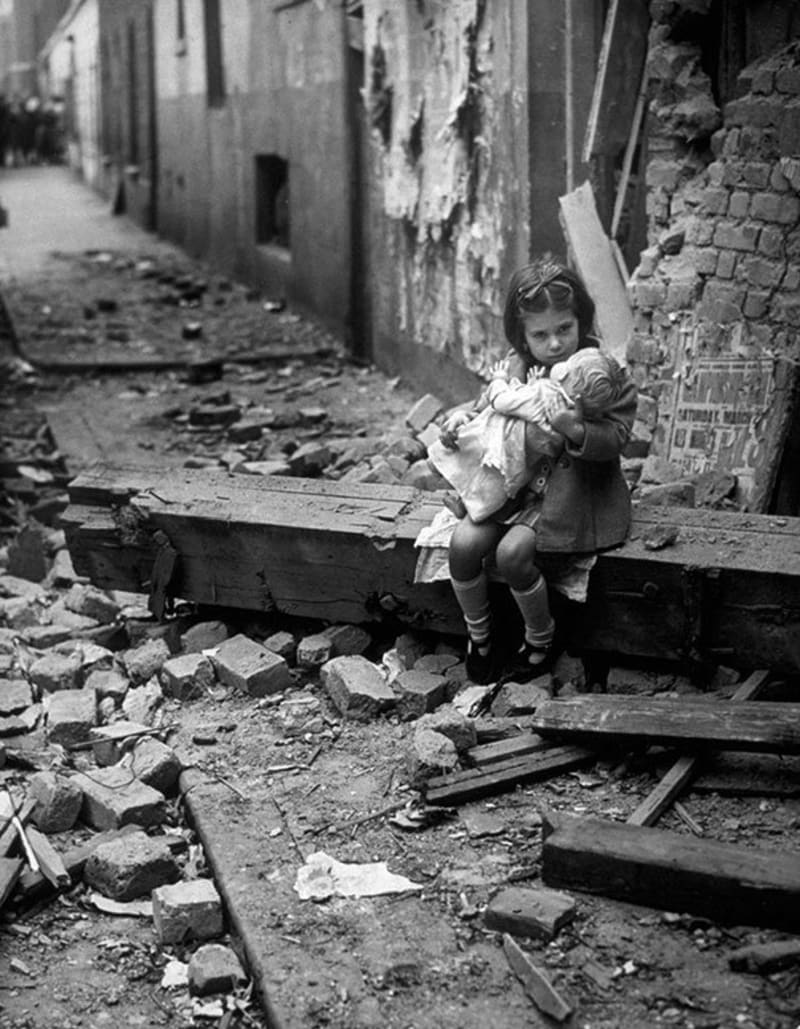 Holčička hrající si s panenkou na místě, kde býval její domov