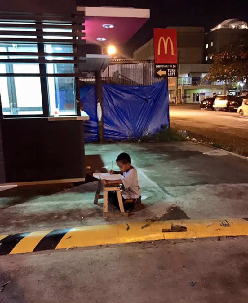 Chlapec se rozhodl na školu nevykašlat a dělá domácí úkoly při světle z místního McDonaldu
