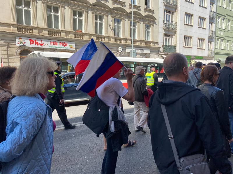 Na mírovém pochodu vlaje i ruská vlajka. Na demonstraci dohlížejí těžkooděnci.