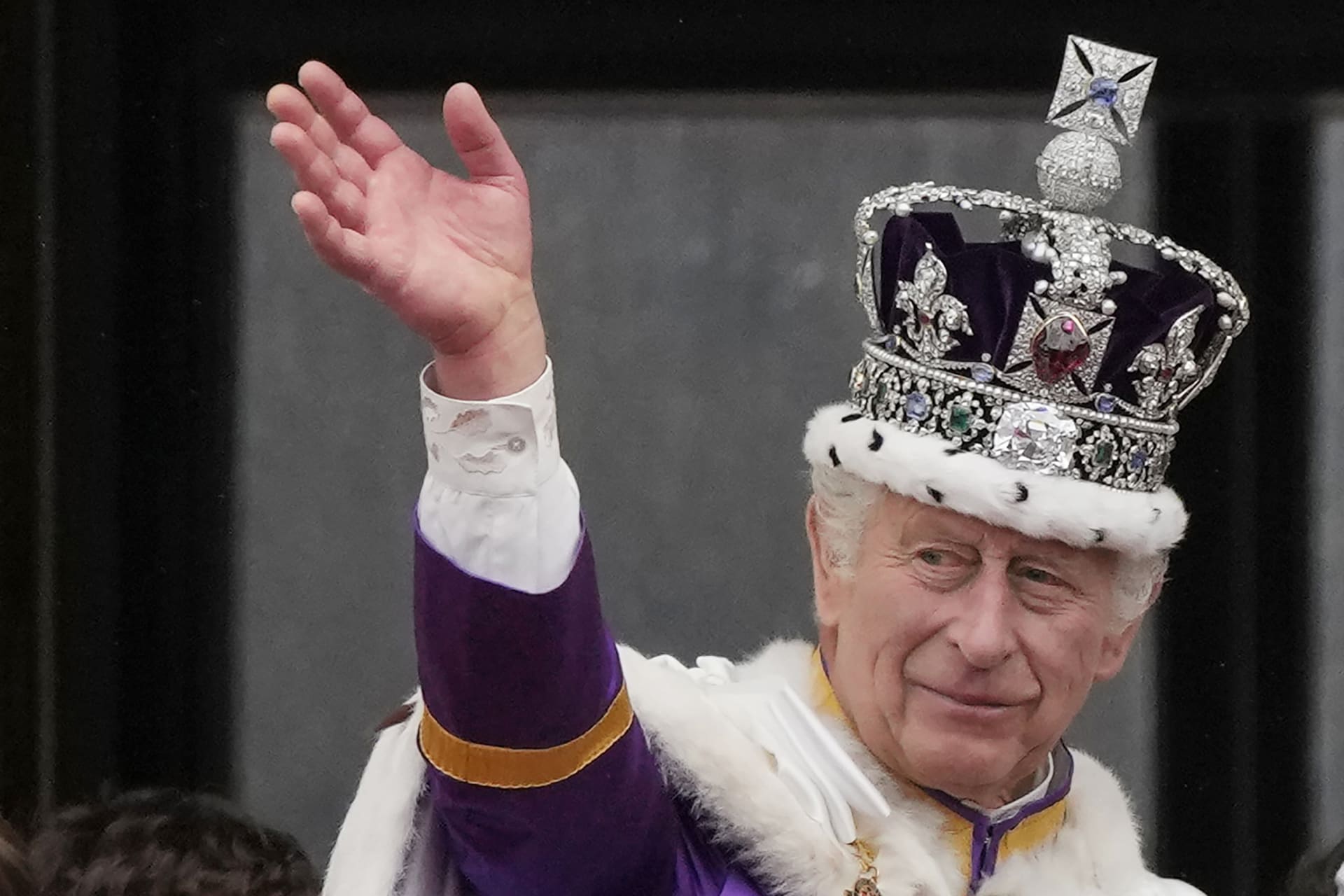 Král Karel III. zdraví davy z paláce.