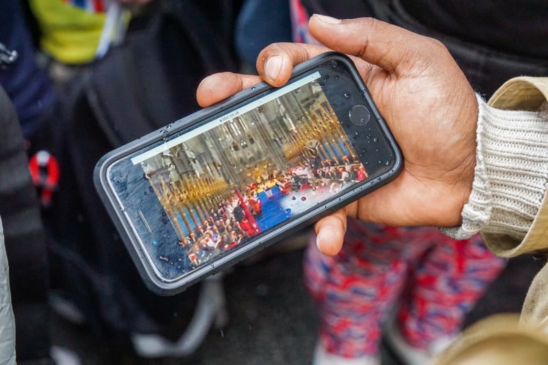 Lidé v davu v centru Londýna sledovali korunovaci na svých mobilech.