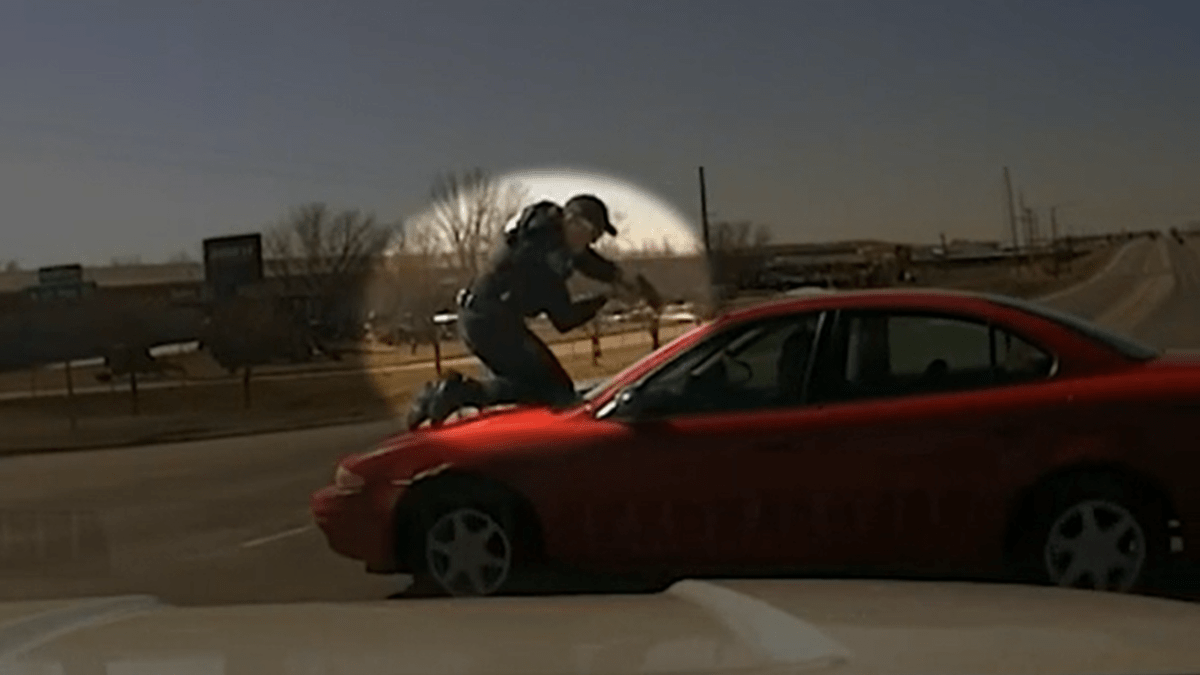 Policista na kapotě vozu se snaží zastavit prchajícího muže