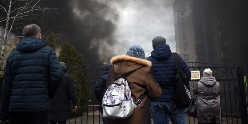 Místní sledují kouř stoupající z požáru, který způsobily trosky raket dopadajících na dvůr obytného domu v Kyjevě. (9. 3. 2023)