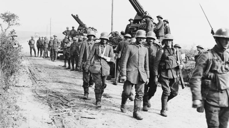 Zajatí němečtí vojáci procházejí kolem protiletadlových děl