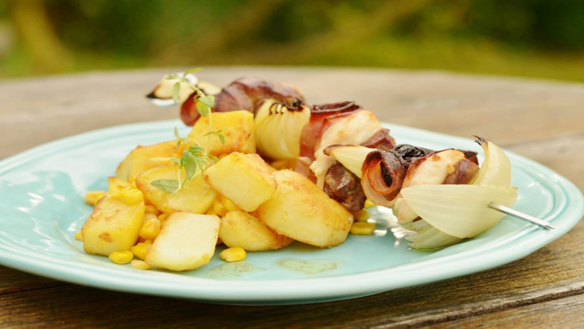 Kuřecí špíz se sušenými švestkami a slaninou a máslové brambory s kukuřicí.