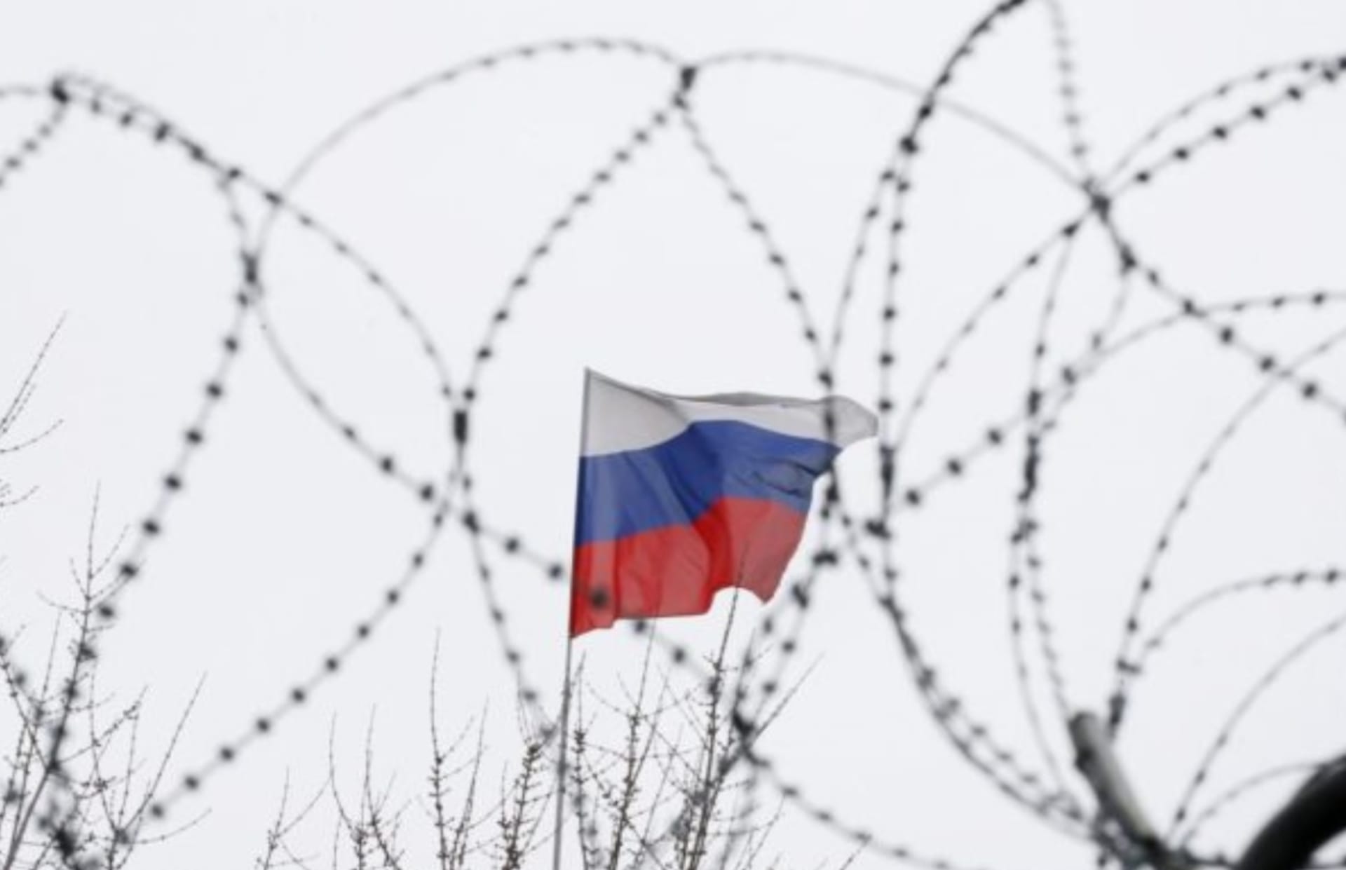 Ilustrační foto: ruská vlajka za ostnatým drátem