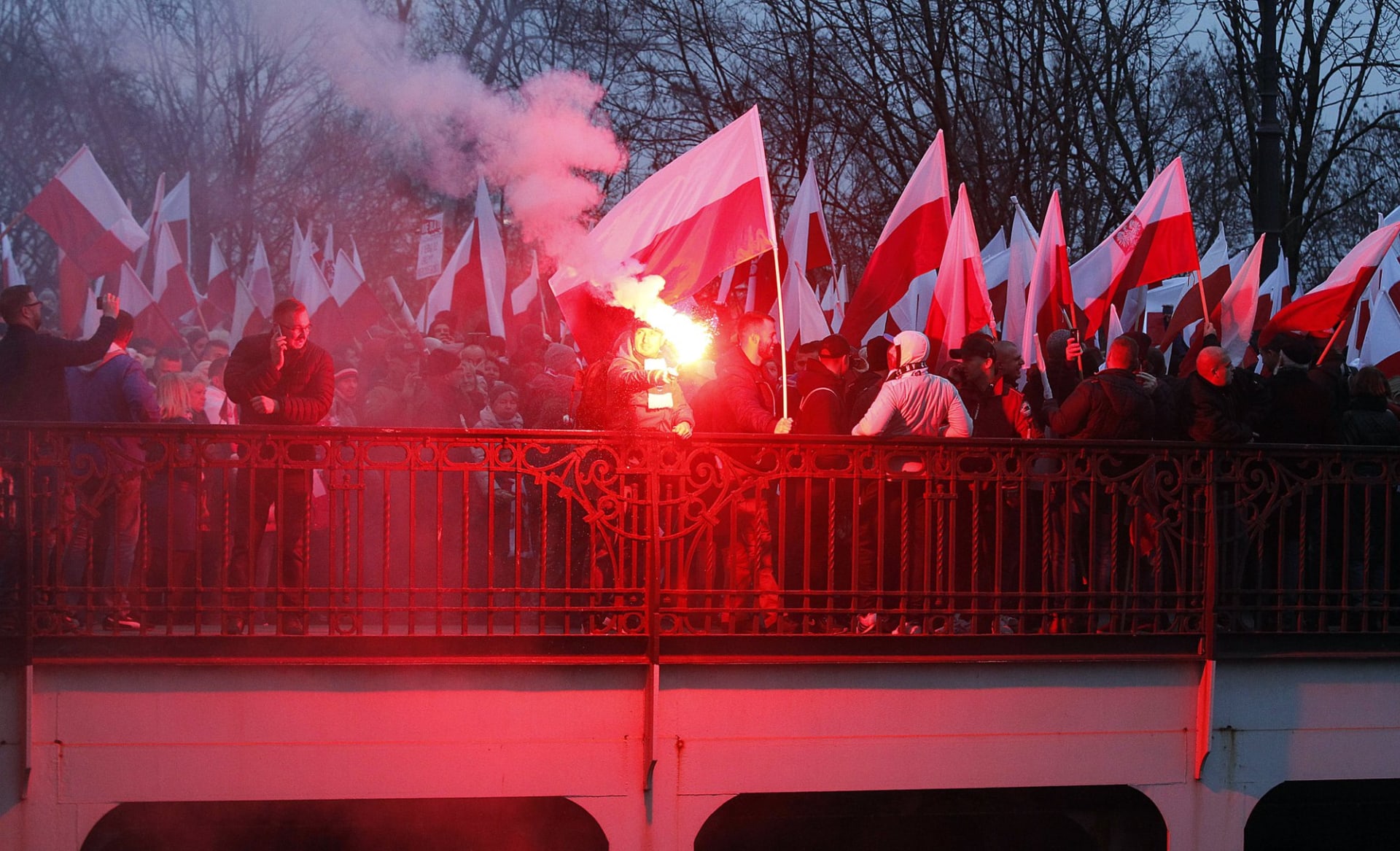 účastníci průvodu s polskými vlajkami a světlicemi