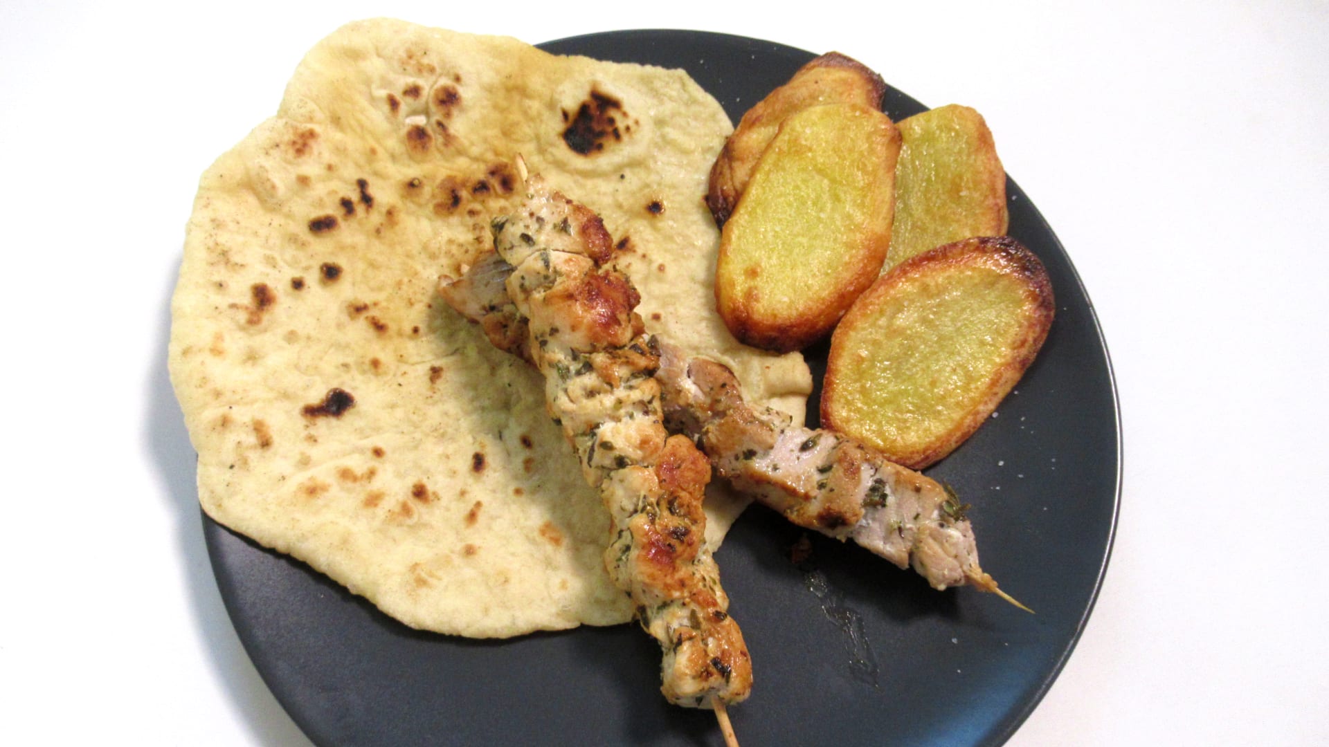 Souvlaki, pečené plátky brambor, pita chléb, tzatziky