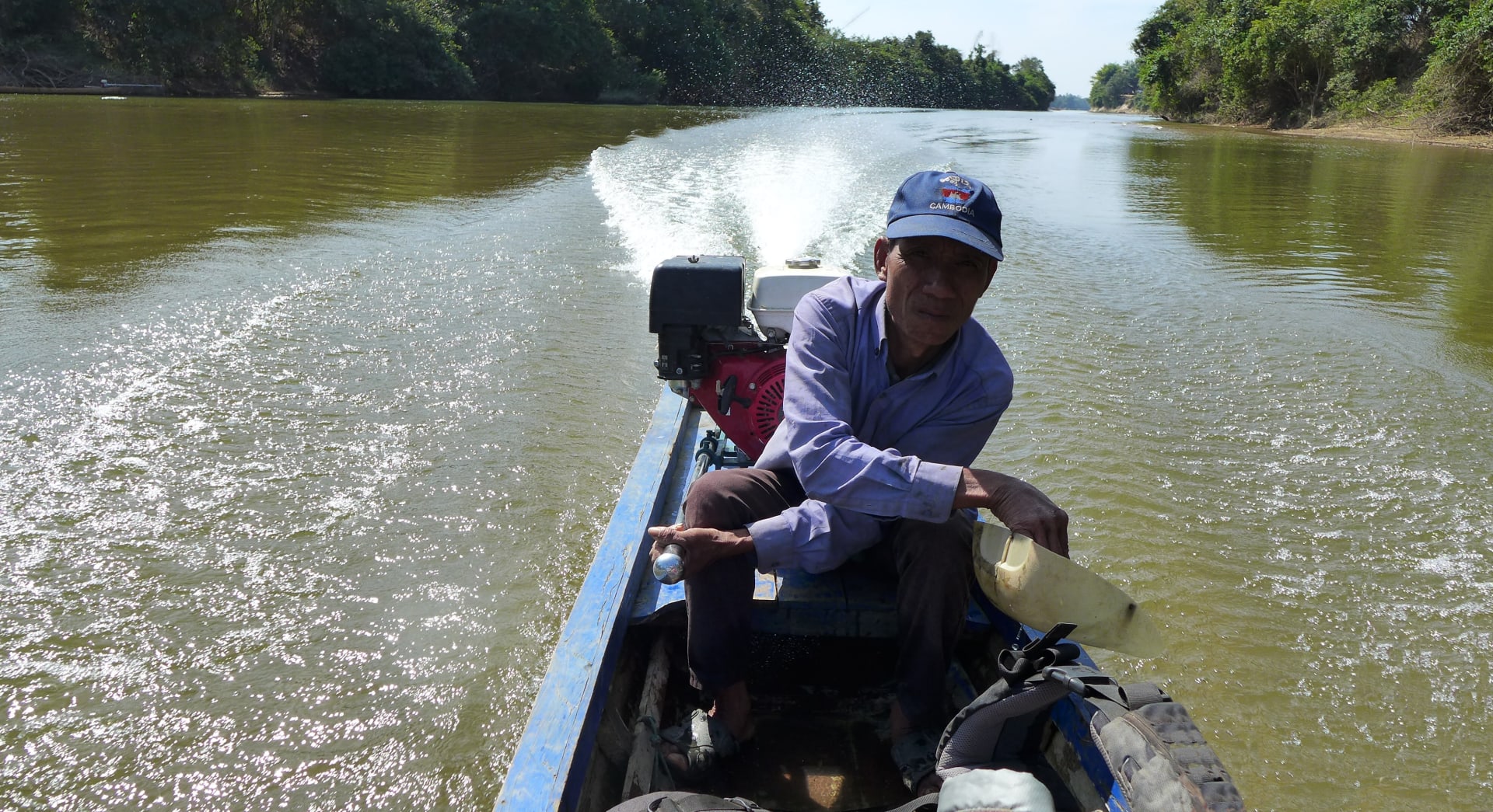 kapitán jednou rukou kormidloval, zatímco druhou vyléval vodu z loďky ven. NP Virachey, Kambodža