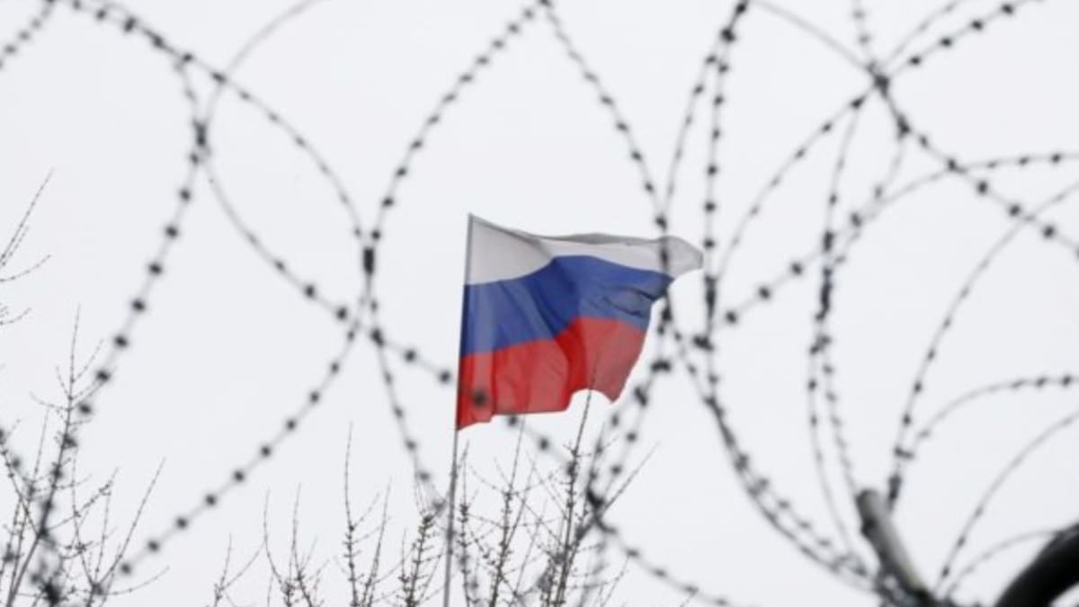 Ilustrační foto: ruská vlajka za ostnatým drátem