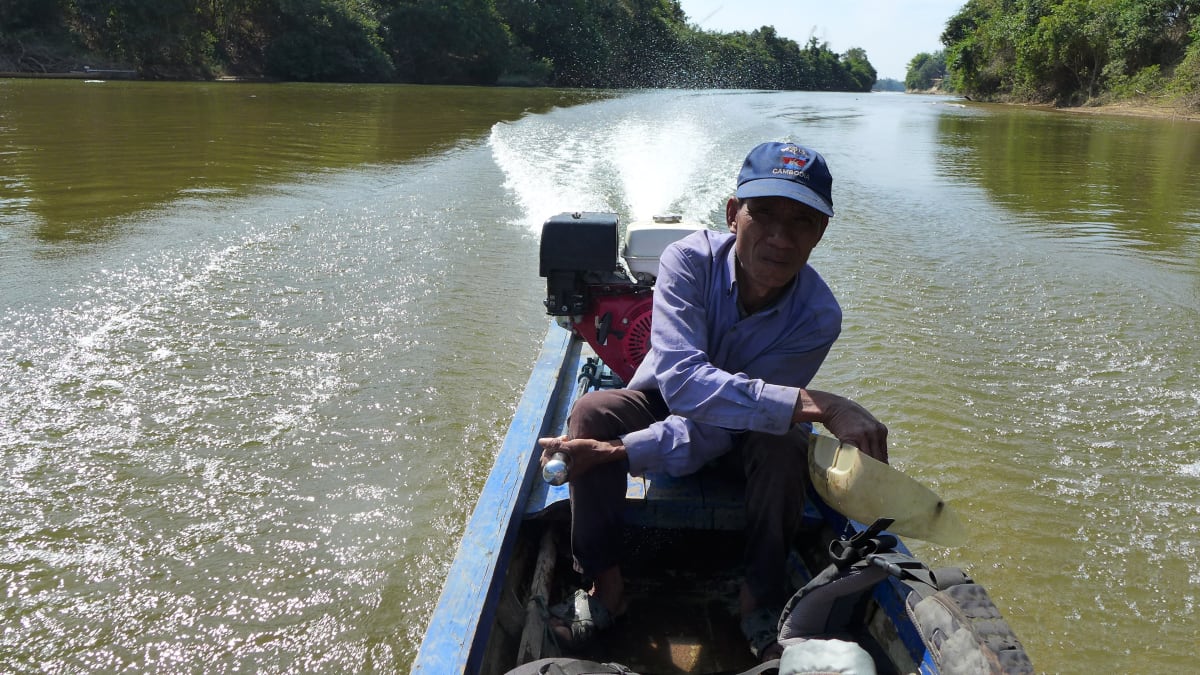 kapitán jednou rukou kormidloval, zatímco druhou vyléval vodu z loďky ven. NP Virachey, Kambodža
