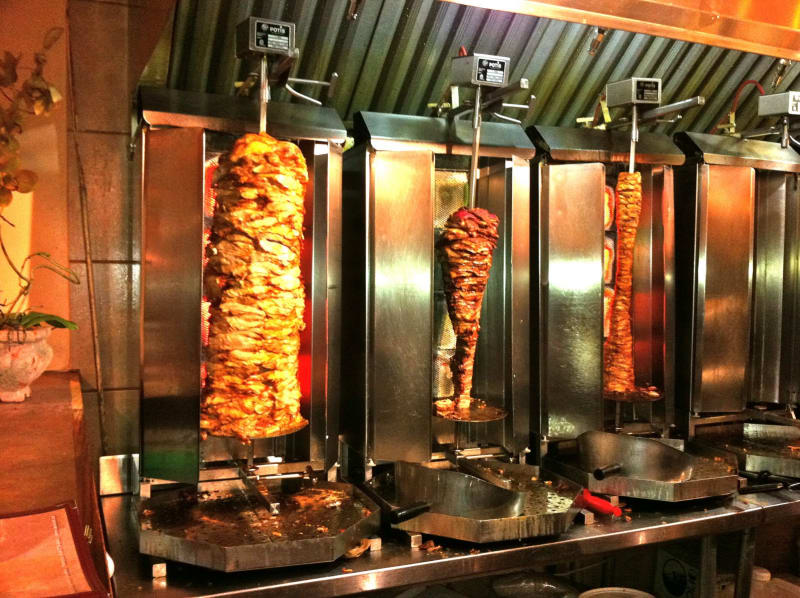 Kebab i gyros se grilují na otočném grilu a odřezávají se hotové kousky masa. FOTO: CK Alex