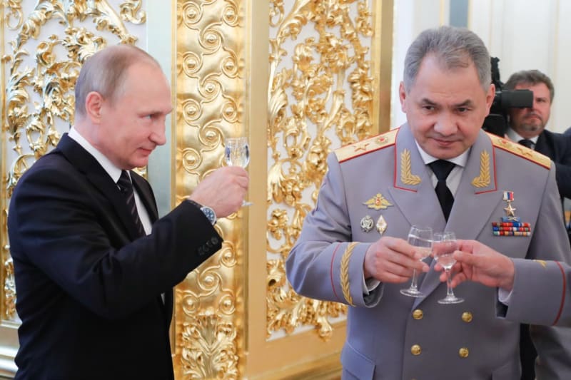 Vladimir Putin (vlevo) a exministr obrany Sergej Šojgu s panákem vodky
