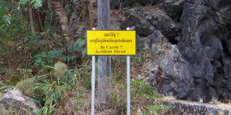 Cedule připevněná na stálo - Pozor, nehoda před vámi. Laos