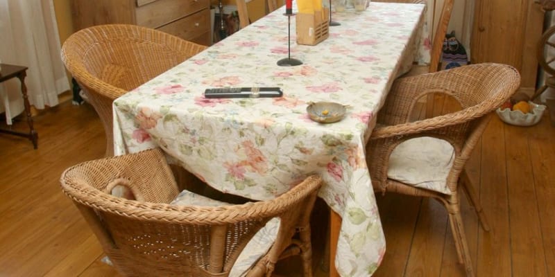 V jídelně je ratanové sezení a bytelný dřevěný stůl