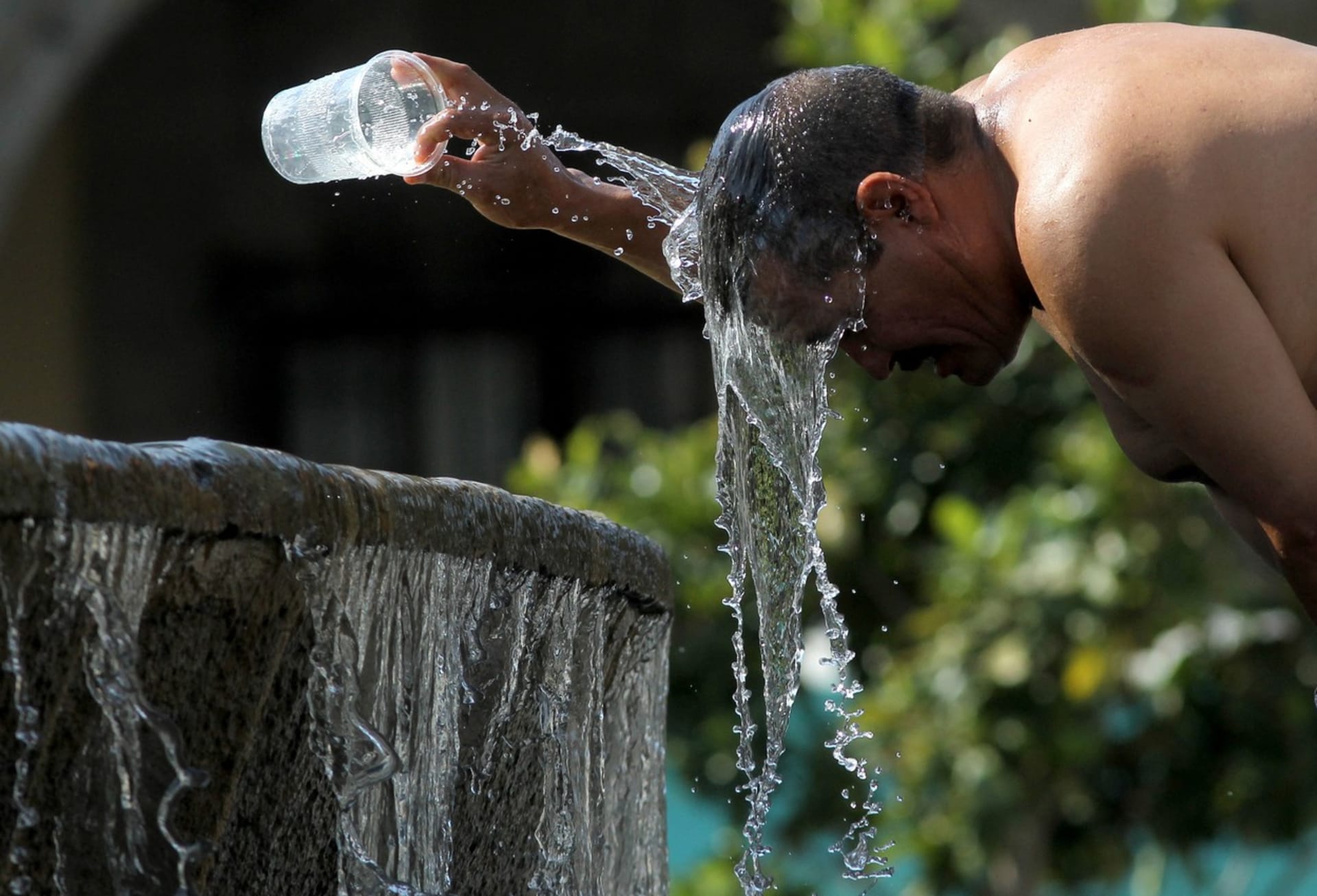 Muž v Mexiku se v horku ochlazuje vodou.