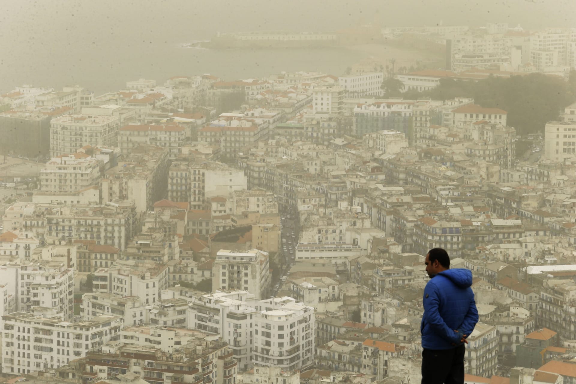 Muž pozoruje oblak písečného prachu ze Sahary v Alžírsku. Středomoří však čekají horší časy s ještě vyššími teplotami.