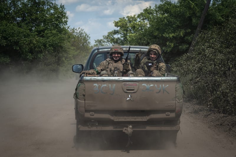 Smějící se ukrajinští vojáci jedoucí u frontové linie poblíž Bachmutu