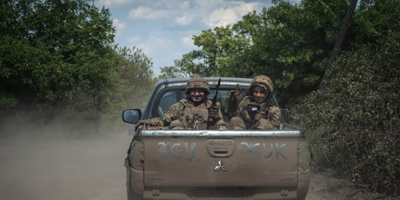 Smějící se ukrajinští vojáci jedoucí u frontové linie poblíž Bachmutu