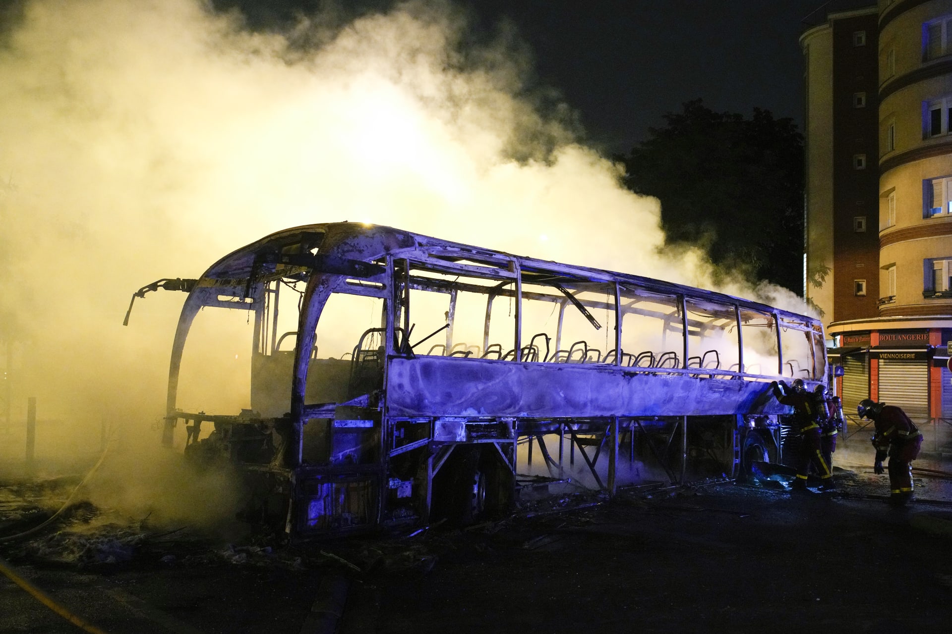 Zasahující jednotky hasí autobus, který protestující zapálili ve městě Nanterre (1. 7. 2023).