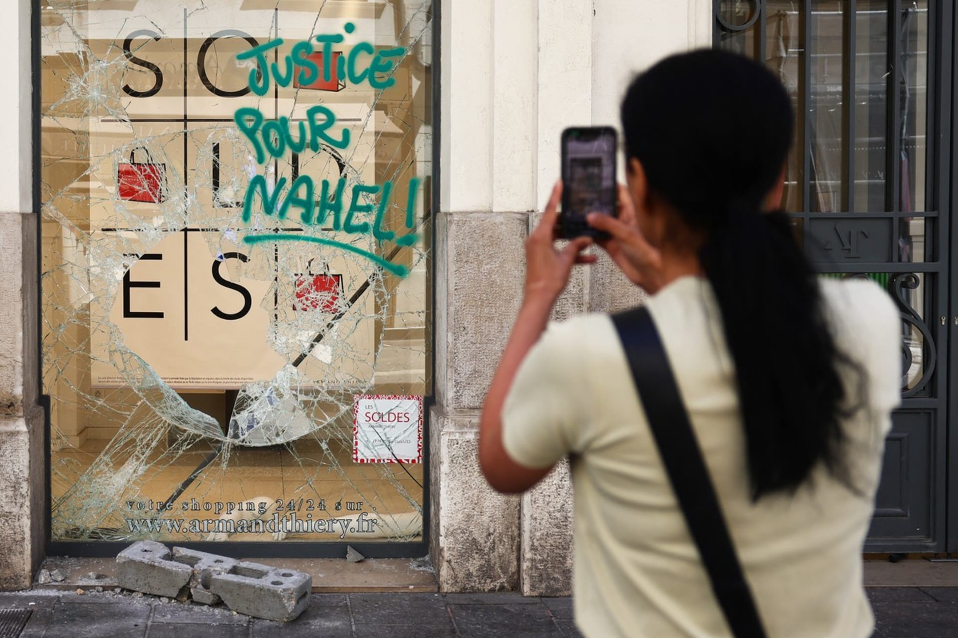 Vyrabovaný obchod s nápisem „spravedlnost pro Nahela“ na rozbité výloze (1. 7. 2023).