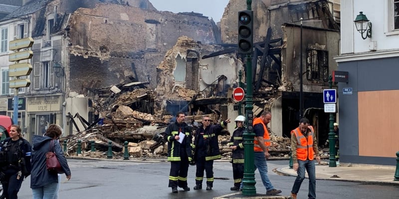 Hasiči prohlížejí zdevastovanou budovu lékárny v Montargis (1. 7. 2023).