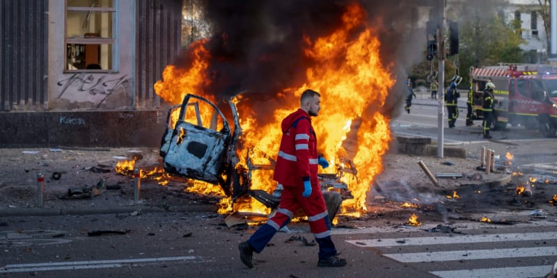 Ukrajinský záchranář jde kolem hořícího auta po ruském bombardování Kyjeva. (11. října 2022)