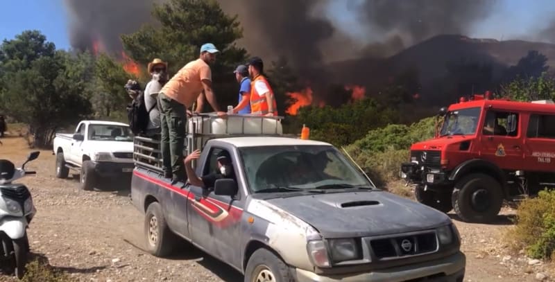 Reportér CNN Prima NEWS se společně s dalšími lidmi přesouvá do bezpečné vzdálenosti od ohně.