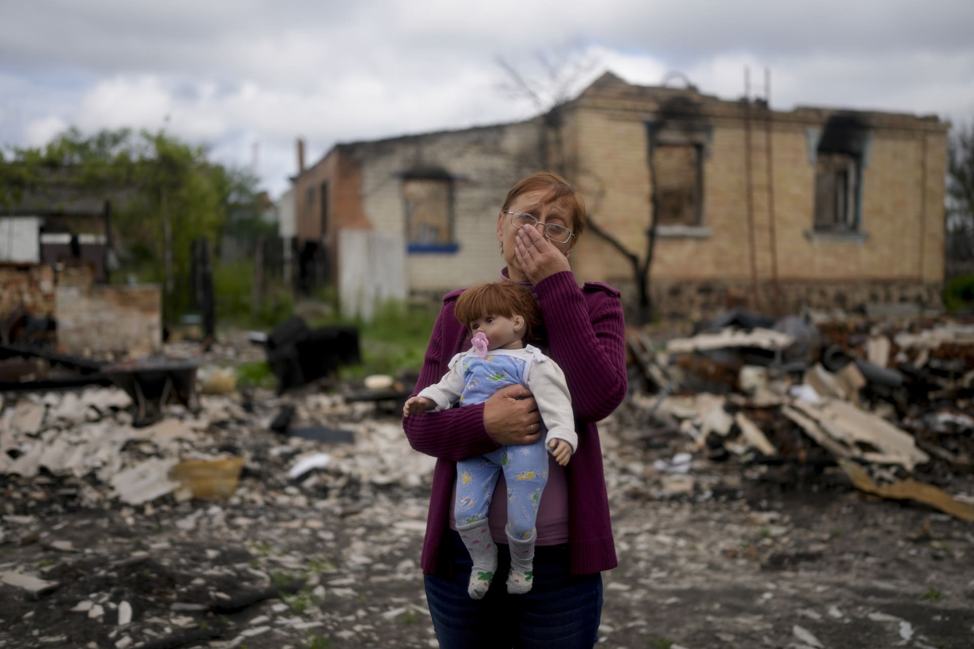 Žena drží panenku své vnučky. Byla to jedna z mála věcí, které se jí podařilo zachránit z jejího domu, zničeného ruským ostřelováním.